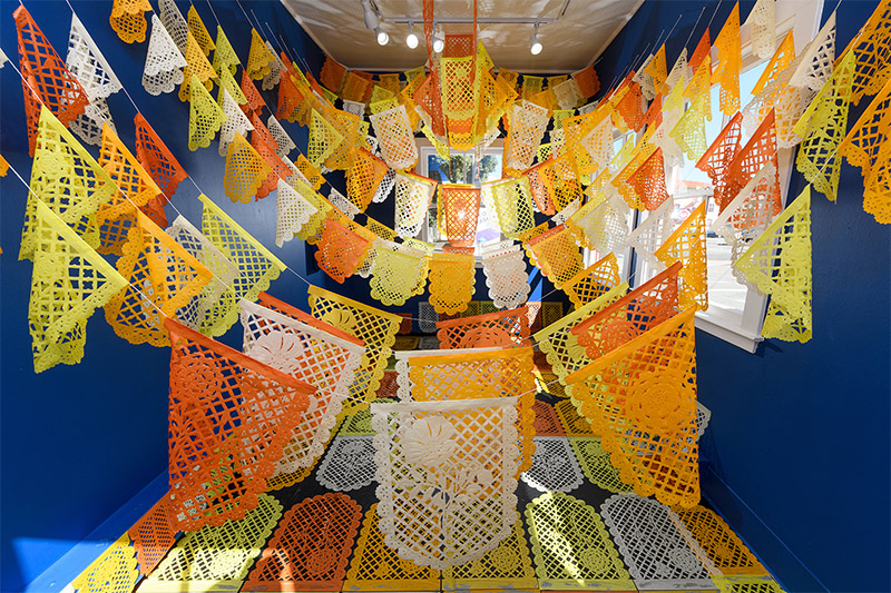 Colorful papel picado fine paper installation in The Guardhouse in San Francisco, titled Karnalitas de Oro: California Poppy and Cempasúchil